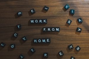the words "work from home" spelled out in black tiles against a wood background