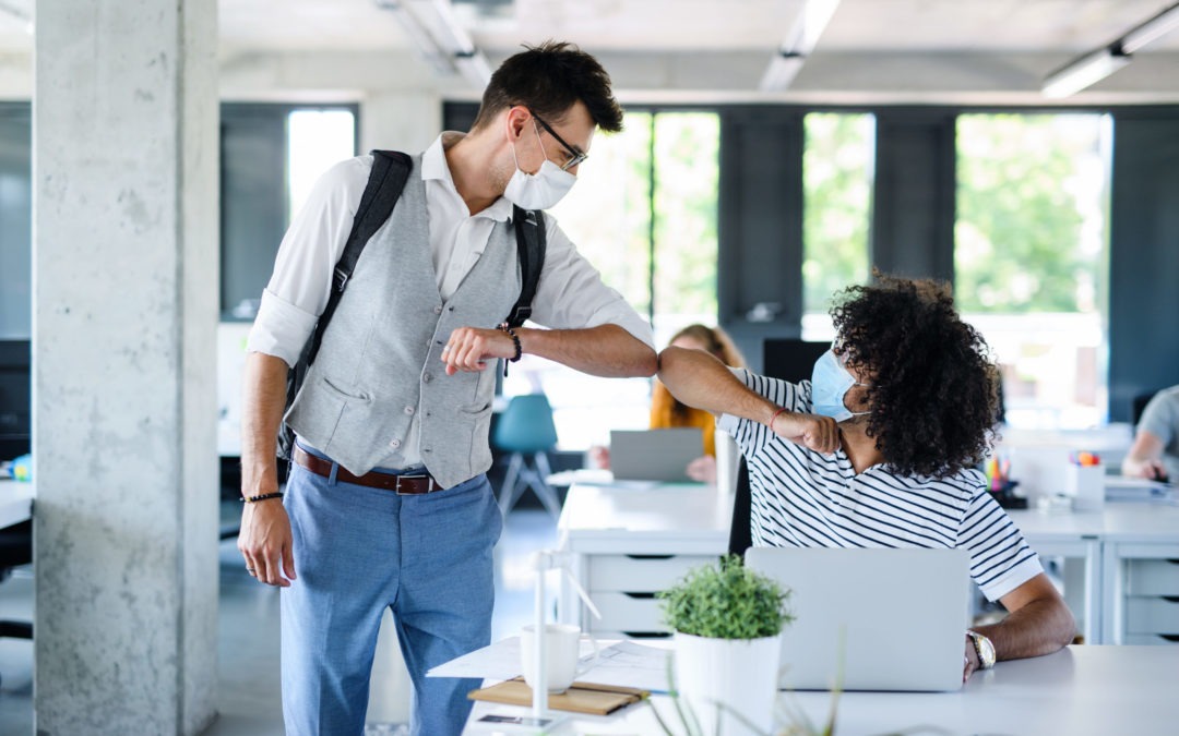 two young adults going back to work after covid greeting each other by touching elbows
