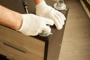up close photo of person's hands wearing white gloves performing Furniture Installation Services