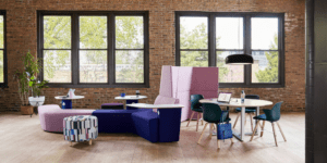 office with brick walls, pink divider wall between lounge style work station and table and chairs work station