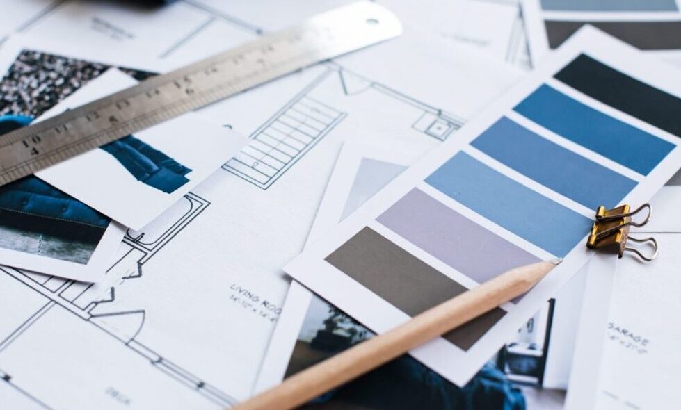 Interior designers working table, an architectural plan, a color palette, furniture and fabric samples in blue color. Drawings and plans.