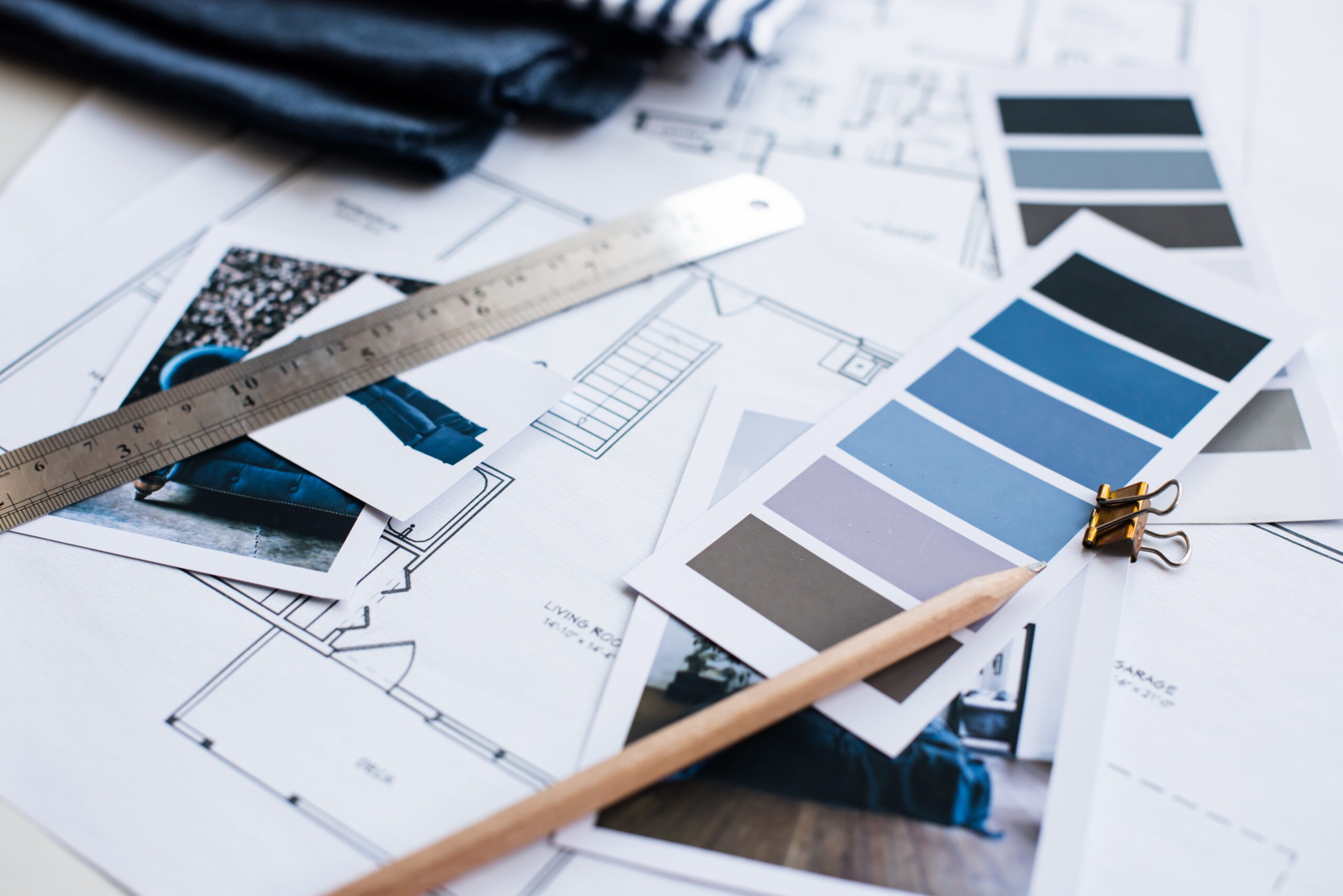 Interior designers working table, an architectural plan, a color palette, furniture and fabric samples in blue color. Drawings and plans.