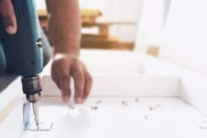 Man is working with furniture assembly using electric screwdriver commercial furniture installation - technician onsite work using hand tools concept