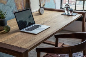 Stylish interior design of office space in loft apartment with wooden desk, chair, office supplies, laptop, plants and elegant accessories. Modern home office decor. wooden desk that needs repair