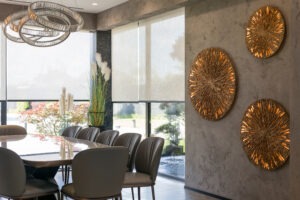 Roller blinds in the interior. Automatic solar shades large size on the window. Modern interior with wood decor panels on the wall. Green plants in hi-tech flower pots. mororized shades for home or office.