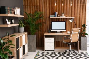Comfortable workplace with computer near wooden wall in stylish room interior.