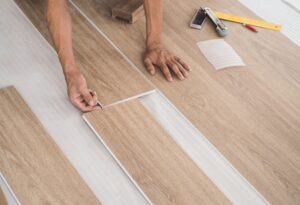 a contractor laying down luxury vinyl flooring that mimcs the look of real wood