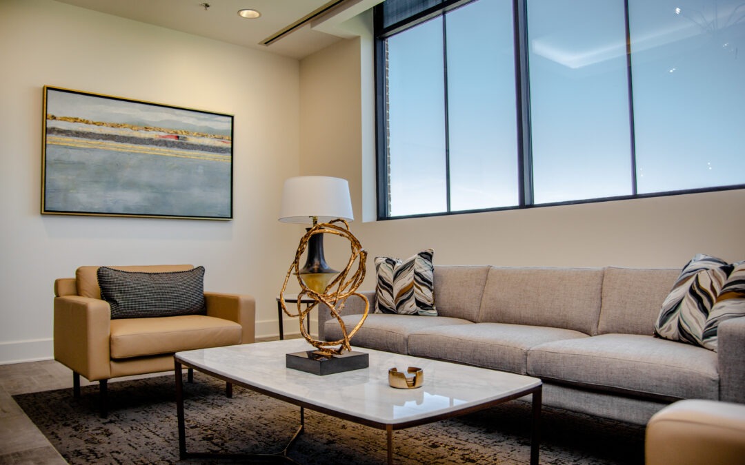 Office Waiting Area Decorated with thoughtful hospital interior design. brown leather chairs, neutral couch, calming photo on the wall.