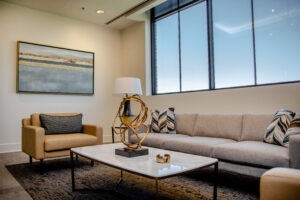 Office Waiting Area Decorated with thoughtful hospital interior design. brown leather chairs, neutral couch, calming photo on the wall.