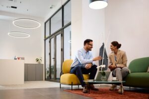two coworkers sitting across from each other in comfortable chairs in a hybrid office design