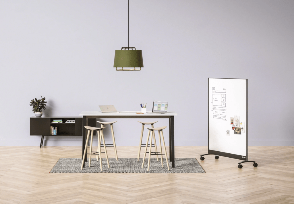 tall desk with 4 stools around it and a portable white board